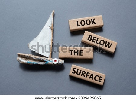 Look below the surface symbol. Concept word Look below the surface on wooden blocks. Beautiful grey background with boat. Business and Look below the surface concept. Copy space
