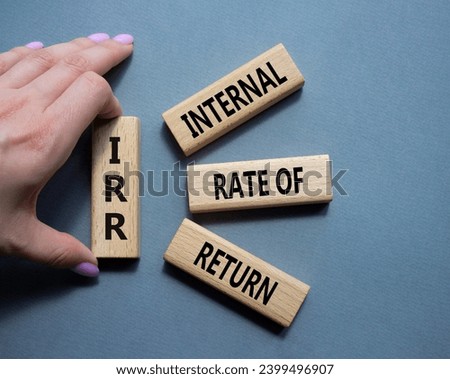 IRR - Internal Rate of Return symbol. Concept word IRR on wooden cubes. Businessman hand. Beautiful grey background. Business and IRR concept. Copy space.