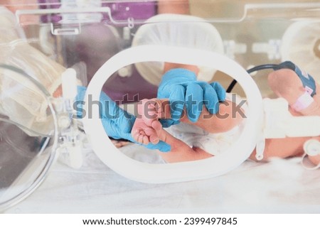 Newborn baby in intensive care unit in medical incubator. Macro photography of child's legs. Concept of saving newborn. Work of intensive care doctors.