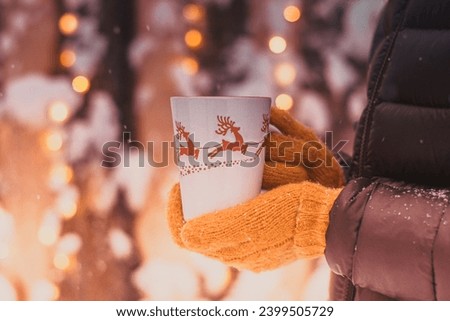 Woman holding mug with mulled wine or hot chocolate at christmas market.