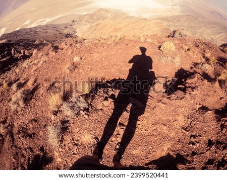 Picture of human shadow on sandy, orange, desert ground at sunny day,