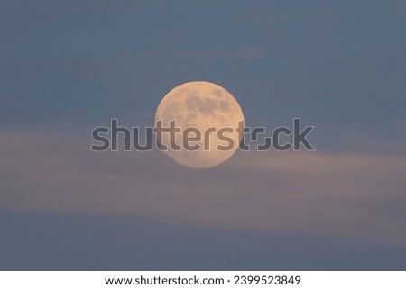 Full moon between clouds at dusk