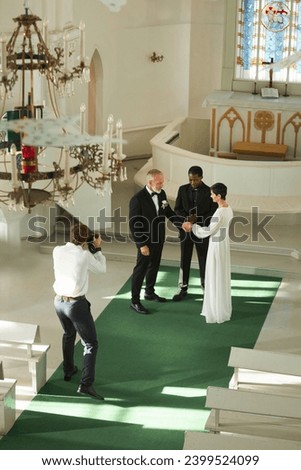 High angle view of wedding ceremony in church with photographer taking pictures on senior couple at altar