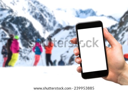 smartphone in the hands of a woman and a group of people on skis
