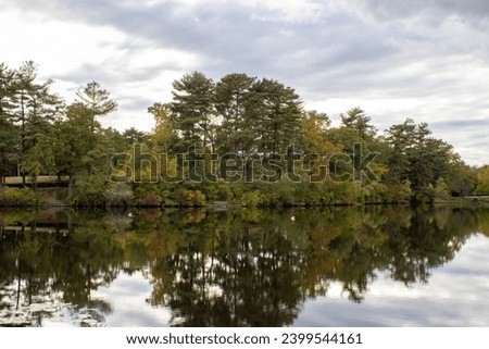 photo captures the essence of autumn with vibrant leaves adorning the trees, their fiery hues mirrored in the calm, glassy surface of a tranquil lake.