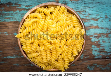 Raw pasta in wooden bowl on wood background - process old dark style picture 