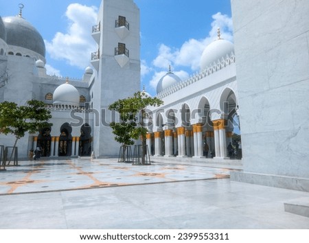 The splendor of the Syech Zayed Mosque building in the city of Surakarta, Central Java, is elegant and you can see some leaves from the trees around it and the bright blue sky and white clouds  Royalty-Free Stock Photo #2399553311