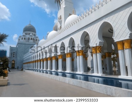 The splendor of the Syech Zayed Mosque building in the city of Surakarta, Central Java, is elegant and you can see some leaves from the trees around it and the bright blue sky and white clouds  Royalty-Free Stock Photo #2399553333