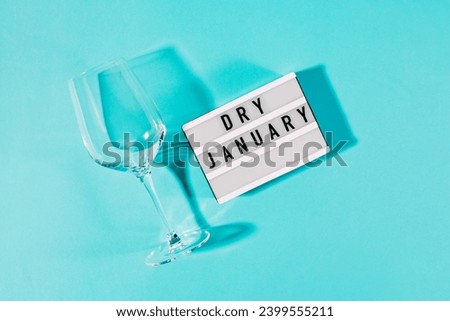 Text Dry January on the decorative lightbox and empty wine glass isolated on blue background, top view Royalty-Free Stock Photo #2399555211