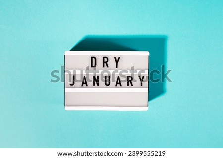 Text Dry January on the decorative lightbox isolated on blue background, top view. Mindful drinking