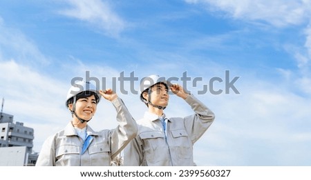 A group of Asian engineers looking up at the blue sky. Royalty-Free Stock Photo #2399560327