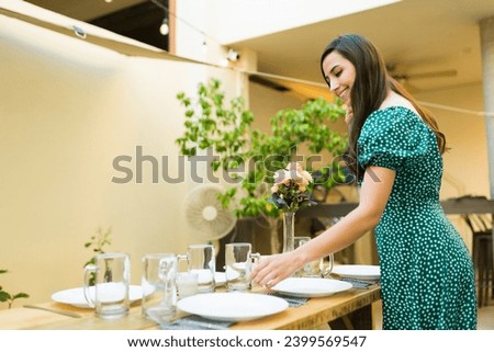 Latin attractive woman smiling while preparing the table to host a dinner in her backyard before receiving her friends
