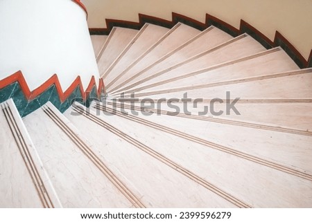 An indoor circular marble staircase in the hotel with a wooden handrail. Luxury classic style staircase with railing in a hotel.