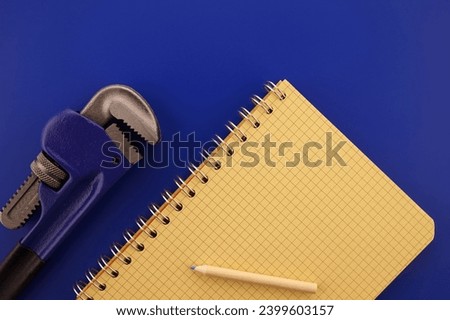 Renovation, building, manufacturing, production or repairs flat lay concept with an arrangement of two assorted wrenches, pencil and note book
