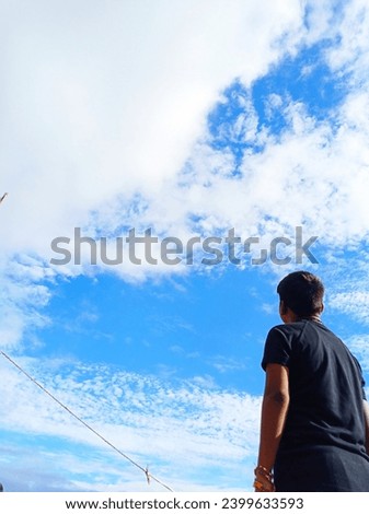 A pristine canvas of clear blue sky serves as the perfect backdrop for a photo featuring a delighted boy. His joyous presence enhances the simplicity of the scene, embodying the boundless possibilitie
