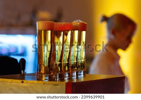 glasses of beer with blurry waitress in the background at an evenening event