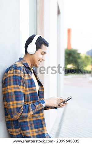 Vertical photo of a college student using phone and listening to music