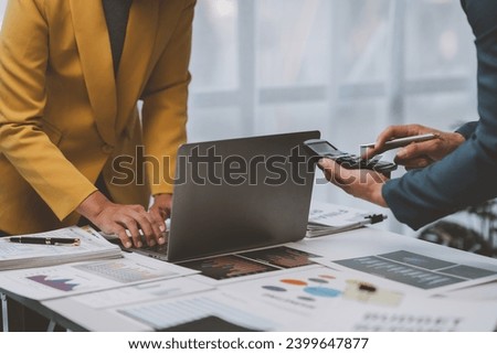 Two Asian businessmen discuss the working information of a financial investment project. Marketing and growth strategies and company revenue calculations Save data to a laptop computer in the office.