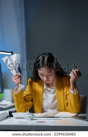 Asian businesswoman or female office worker who is angry, irritated, stressed over a failed job. and crumpled documents in her hands at her desk. Depression overworked Office Syndrome.