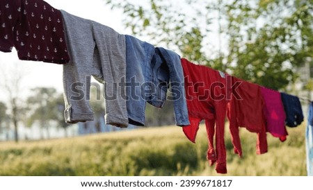After being washed, Colorful clothing dries on a clothesline in the yard outside in the sunlight. Clothesline with freshly washed clothes outdoors in the morning