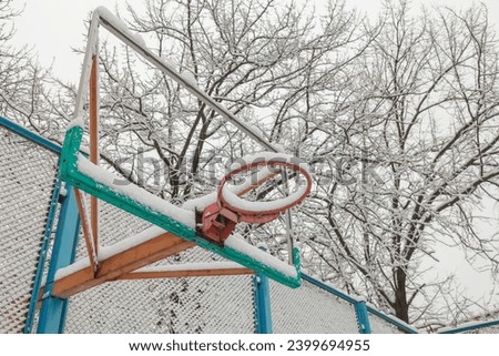 An old basketball hoop is covered with snow. The first snow in the city