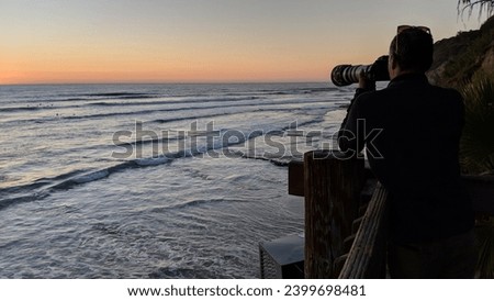 Photographer taking a picture of surfers with a telephoto lens at Swamis Reef Surf Park Encinitas California.