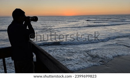 Photographer taking a picture of surfers with a telephoto lens at Swamis Reef Surf Park Encinitas California #2.
