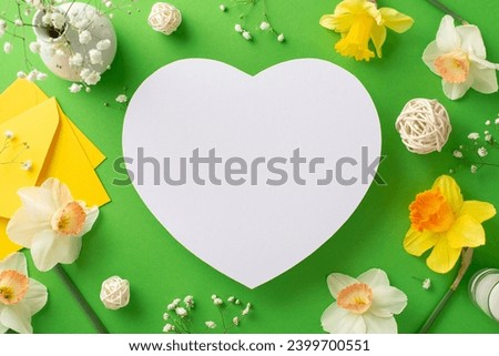 Welcome spring's awakening with narcissus and gypsophila. Top-view image captures fresh flowers and decorations on a green isolated background, heart-shaped frame ready for text or advertising Royalty-Free Stock Photo #2399700551