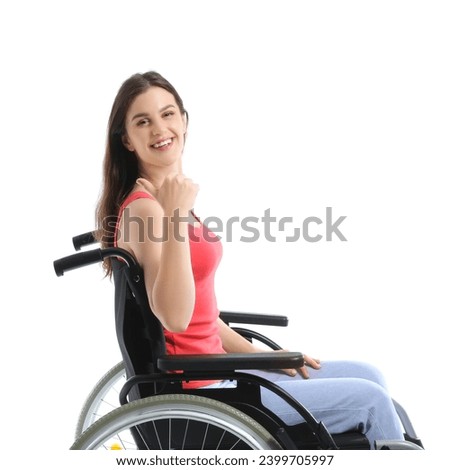 Young woman in wheelchair pointing at something on white background Royalty-Free Stock Photo #2399705997