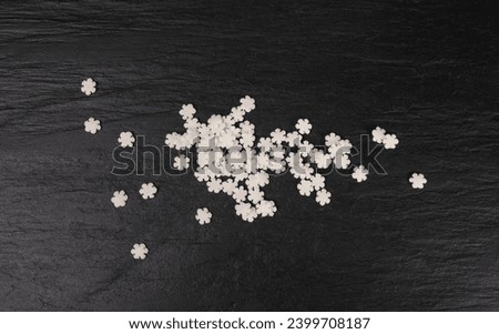 White Snowflake Sprinkles, Scattered Sugar Snow, Decorative Christmas Stars, Ice Xmas Decoration, Winter Confectionery Candy Sprinkle on Black Background Top View