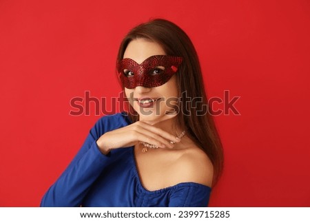 Happy young woman in carnival mask on red background