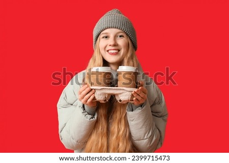 Beautiful young happy woman with paper cups of tea on red background