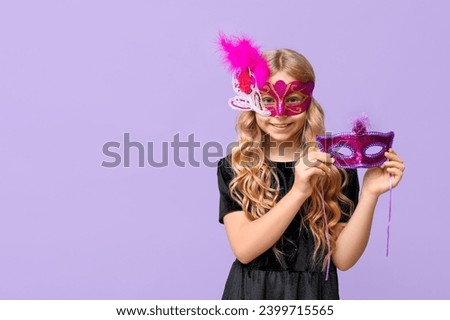 Funny little girl with carnival masks on lilac background Royalty-Free Stock Photo #2399715565