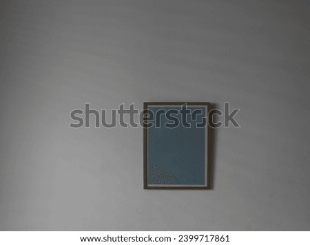 empty Poster hanging on white sunny wall background. living room interior in beige. light device. empty mock up room. wall. Blank wooden vertical frame. mockup gray backdrop. Natural light. shadow 