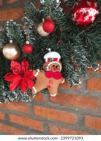 Christmas ornaments in the form of gingerbread dolls stick to the red brick walls