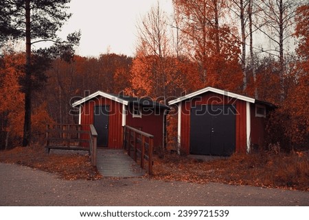 Two red little Scandinavian houses in the orange autumn forest