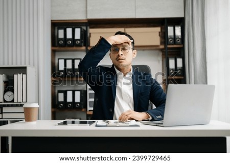 Overworked young Asian businessman office worker suffering from neck pain after had a long day at her office desk. office syndrome concept
