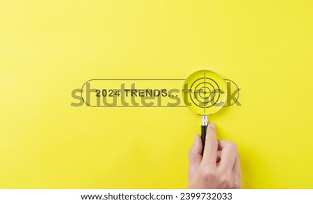 Trends 2024 year concept. Hand holding magnifying glass with 2024 trend searching bar for optimization 2024 business marketing trends and business plan in new year. Find information and new ideas.