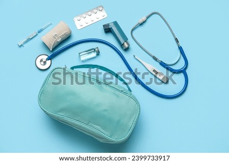 First aid kit and pills on blue background Royalty-Free Stock Photo #2399733917