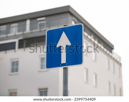 One-way street sign in Germany. The white arrow on the blue square is pointing ahead. The travel direction is straight on.