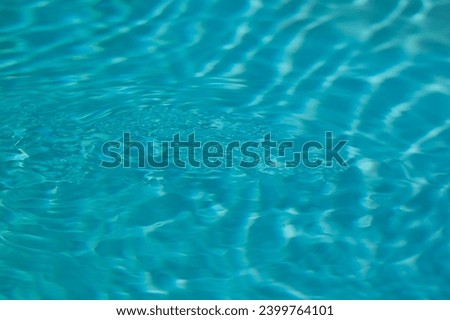 De-focused blurred transparent blue colored clear calm water surface texture. Abstract nature background.