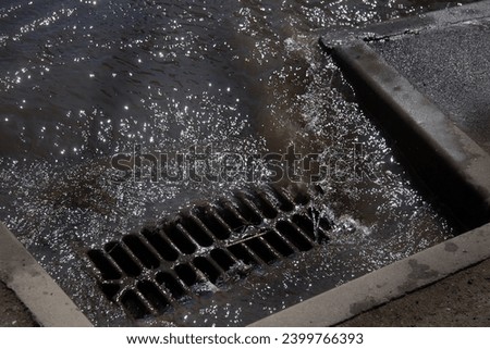 Flow of water during heavy rain and clogging of street sewage. The flow of water during a strong hurricane in storm sewers. Sewage storm system along the road to drain rain into the drainage system