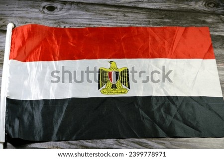 The national flag of Egypt, a tricolour consisting of the three equal horizontal red, white, and black bands, The flag bears Egypt's national emblem, the Egyptian eagle of Saladin in the white band