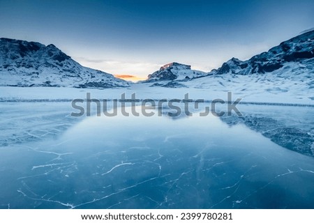  A mountainous, snow-covered landscape with a frozen lake in the foreground. Royalty-Free Stock Photo #2399780281
