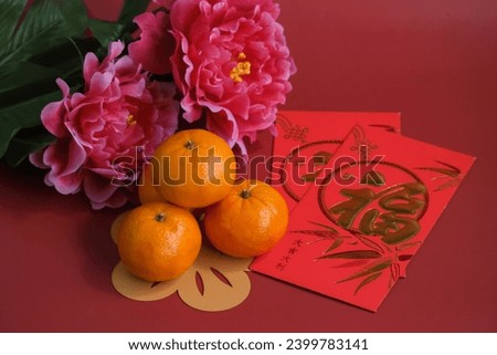 Chinese New Year of the dragon festival concept. Mandarin orange, red envelopes and gold ingot decorated with plum blossom on red background. Chinese character "fu" which stands for luck.