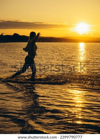 Silhouette of the woman walking in the water during beautiful sunset