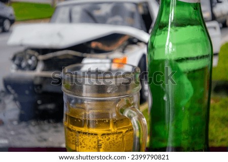 A drink driving concept with a pint and bottles of beer and a picture of a crashed car in the background.