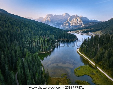 Aerial view of Lago di Misurina  and the panorama of the Dolomites in background. Sunny morning, blue sky, view across the lake and hiking paths.  Royalty-Free Stock Photo #2399797871