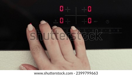 Woman hand includes an electric stove. Touch panel of induction cooker. Modern technology. Royalty-Free Stock Photo #2399799663