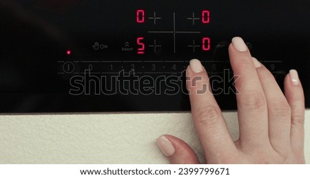 Woman hand includes an electric stove. Touch panel of induction cooker. Modern technology. Royalty-Free Stock Photo #2399799671